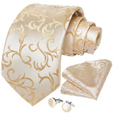 Beige tie with gold floral pattern, matching pocket square, and cufflinks on a white background
