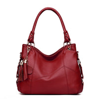 A stylish red leather handbag with a soft silhouette, featuring decorative tassels and silver hardware details.