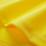 Close-up of vibrant yellow fabric, showcasing its smooth texture and fine stitching detail.