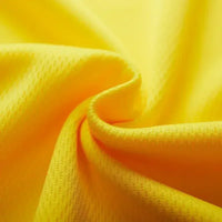 Close-up of vibrant yellow fabric, showcasing its soft, textured surface and gentle folds.