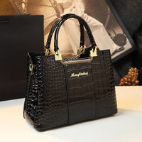 Elegant black handbag with crocodile texture, gold accents, and 'Menglinkat' logo, displayed on a soft surface with a stylish background.