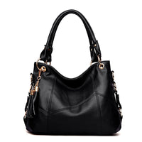 Stylish black leather handbag with gold accents and a decorative tassel, featuring dual handles for versatility.