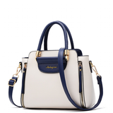 Stylish white handbag with navy accents, dual handles, a detachable shoulder strap, and gold hardware detailing.