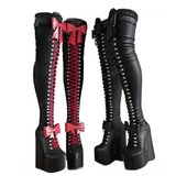 Black knee-high boots with red laces and pink bows, and black platform boots with silver studs on a white background.
