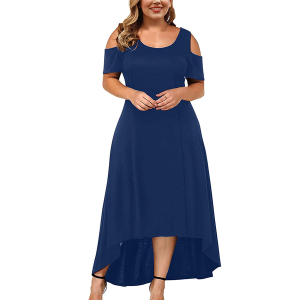 A woman wearing a blue high-low dress with cold-shoulder sleeves stands smiling. She has loose, wavy hair and wears black strappy heels, conveying elegance.