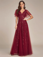 A woman in a burgundy, floor-length gown with sheer, flutter sleeves and leaf patterns.