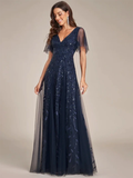 A woman in a navy blue evening gown with short, sheer sleeves stands against a neutral background. The dress features intricate leaf patterns