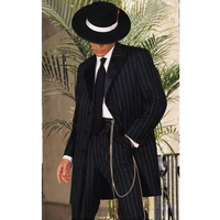 Man in a pinstripe suit and wide-brimmed hat, face shadowed. He stands confidently with plants behind, creating a vintage, stylish atmosphere.