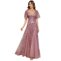 A woman in an elegant mauve gown with delicate lace and floral embroidery. The dress has sheer short sleeves and a flowing skirt, creating a graceful look.