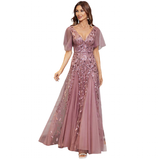 A woman in an elegant mauve gown with delicate lace and floral embroidery. The dress has sheer short sleeves and a flowing skirt, creating a graceful look.