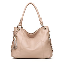 A stylish beige leather handbag with a slouchy design, featuring golden hardware and a decorative tassel charm.