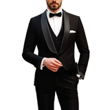 A man in a stylish black tuxedo with satin lapels and a bow tie. He has a pocket square and wears a watch, exuding elegance and sophistication.