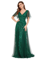 Woman in a floor-length, emerald green gown with a V-neck and cape sleeves, adorned with leaf patterns. She exudes elegance and confidence.