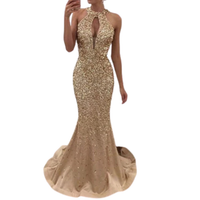 A woman is wearing a sparkling, gold, sleeveless evening gown with a keyhole neckline and a mermaid silhouette, exuding elegance and glamour.