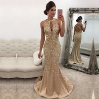 Woman wearing gold evening gown. The dress has a keyhole neckline and a mermaid silhouette, conveying elegance.