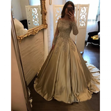 A woman stands in front of a mirror, wearing an elegant, gold lace gown with a full skirt and long sleeves. The room is softly lit, creating a luxurious, sophisticated ambiance.