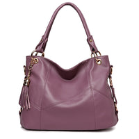 A stylish lavender leather handbag with gold accents and a tassel detail, featuring dual handles for versatile carrying.