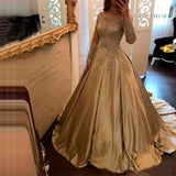 A woman in a luxurious gold ball gown with intricate lace detailing on the bodice and sleeves stands in front of an ornate mirror, conveying elegance.