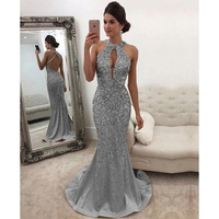 A woman wearing silver gown. The elegant dress features a fitted design with a mermaid silhouette.