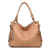 A stylish tan leather handbag with a textured finish, gold hardware, and a decorative tassel.
