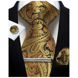 Gold and black paisley tie set with matching pocket square and cufflinks on a white background.