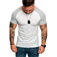 Man wearing a white and gray t-shirt with tattoos on arms, on a white background