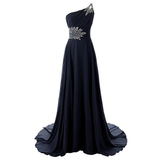 Elegant black evening gown with an asymmetrical neckline, adorned with sparkling silver embellishments on the shoulder and waist. Flows gracefully.
