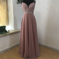 Elegant mauve evening gown with a sequined bodice and thin straps, displayed on a mannequin against a simple indoor setting, conveying sophistication.