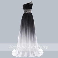 Elegant one-shoulder gown with a gradient from black to white, featuring a rhinestone-embellished shoulder and waist, conveying sophistication.