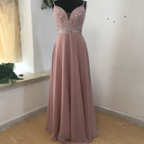 Elegant pink gown on a mannequin, featuring a sparkly beaded bodice with thin straps and a flowing A-line skirt. Soft and graceful setting.