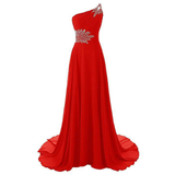 Elegant red evening gown with a one-shoulder design, featuring silver embellishments on the shoulder and waist. The fabric flows gracefully to the floor.