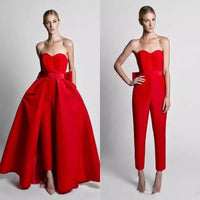 A woman is wearing a bold red outfit, convertible from a strapless gown with a dramatic full skirt to a sleek jumpsuit. The look is elegant and modern.