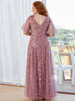 A woman wearing a mauve, floor-length gown adorned with leaf patterns. The scene conveys elegance and serenity.