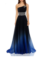 A woman wears a one-shoulder gown, black at the top fading to blue at the bottom. The dress features a jewel-encrusted strap and waist, exuding elegance.