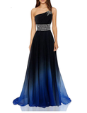 A woman wears a one-shoulder gown, black at the top fading to blue at the bottom. The dress features a jewel-encrusted strap and waist, exuding elegance.