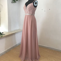 A mannequin displays a sleeveless, floor-length pink gown. The bodice is sequined, with a deep V-neck and a sparkly waistband. Soft, elegant setting.