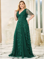 woman wearing an emerald green gown with leaf patterns, standing in a marble-floored room. Natural light from tall windows creates a serene ambience.