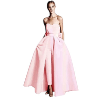 A wearing a strapless, blush pink gown with a fitted bodice and flowing skirt stands elegantly. The dress conveys a classic, formal tone.
