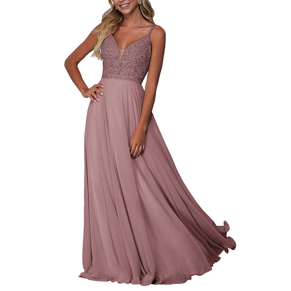 Woman in a flowing, dusty pink evening gown with a sparkling bodice and thin straps. She has long, wavy hair, embodying elegance and grace.