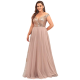 Woman in elegant, floor-length gown with a sequin-embellished bodice and flowing tulle skirt, posing confidently against a white background.