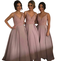 Three women stand side by side, smiling, in matching floor-length mauve dresses with sparkling bodices and pleated skirts, conveying elegance and joy.