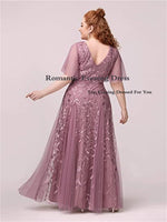 A woman in a romantic mauve evening dress adorned with delicate floral patterns poses elegantly, conveying sophistication and grace.