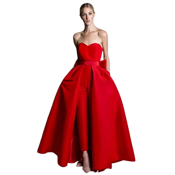 A woman wearing an elegant, strapless red gown with a full-length skirt and a subtle bow at the waist, exuding sophistication and grace.